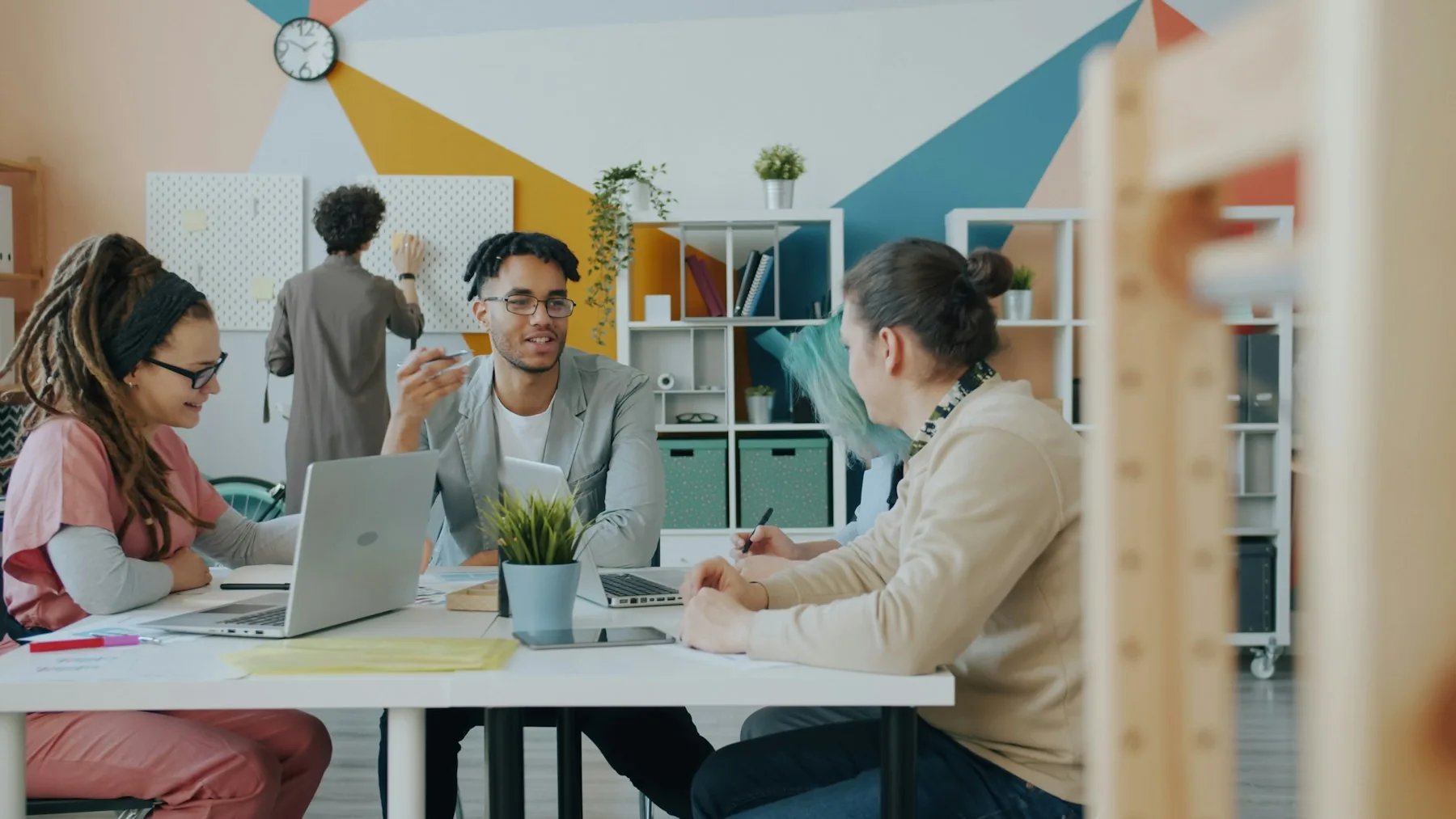 Colleagues exchanging ideas around a table in a colorful shared workspace